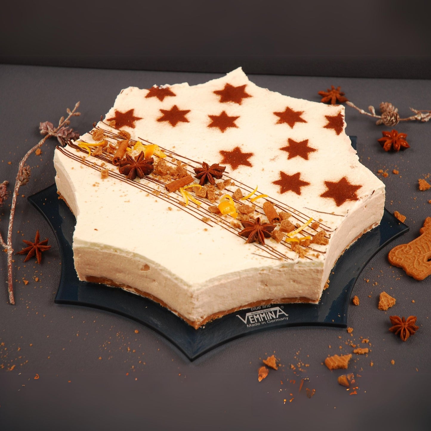 Star-shaped cake on a sleek Cornwall plate, decorated with brown star patterns and spices for a festive look.