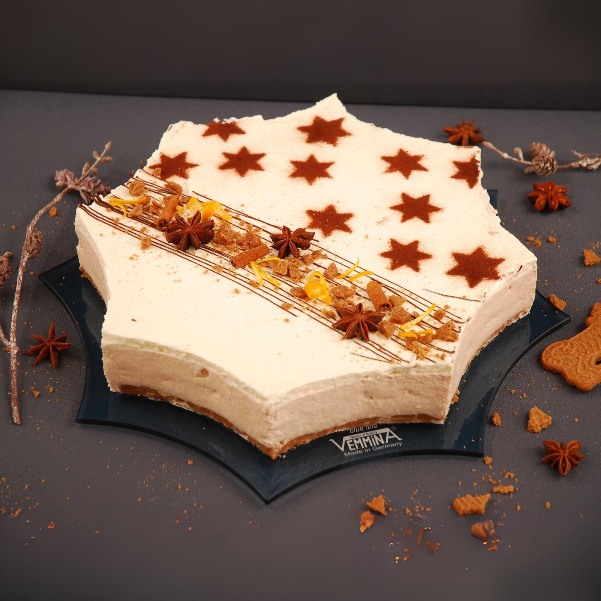 Star-shaped cake on a sleek Cornwall plate, decorated with brown star patterns and spices for a festive look.
